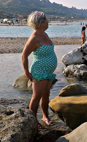 Chubby granny in a short dress on a sea